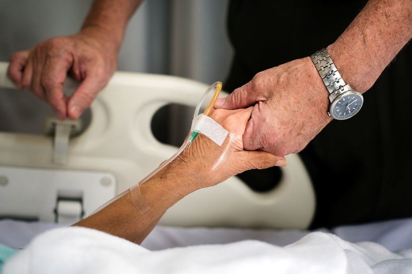 Manos sosteniendo la mano de un paciente hospitalizado