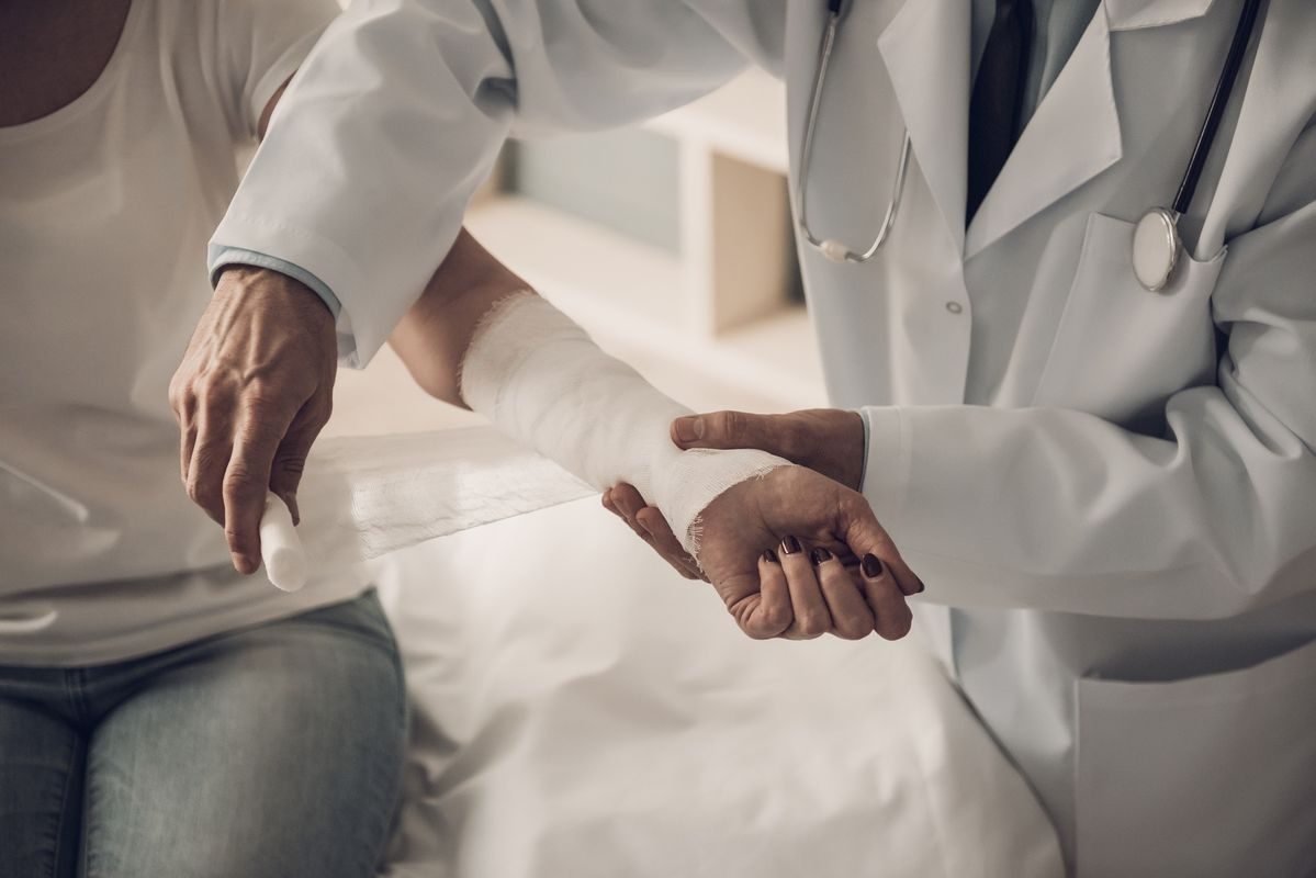 Médica colocando un vendaje en el antebrazo de una paciente durante la consulta